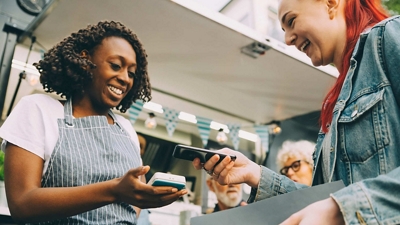 A customer pays with her phone on a wireless point-of-sale terminal at an event’s food stand.