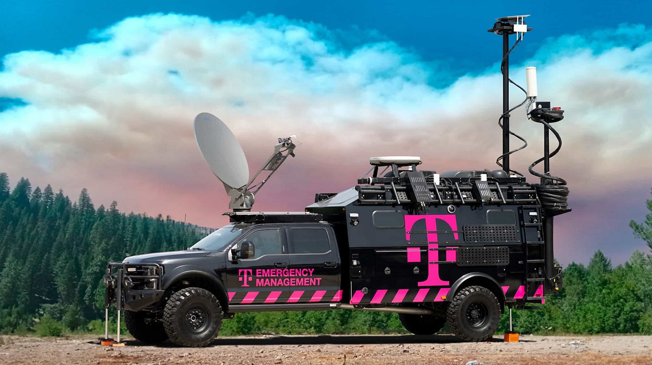 A T-Mobile emergency management truck deployed on a primitive road in a forest.