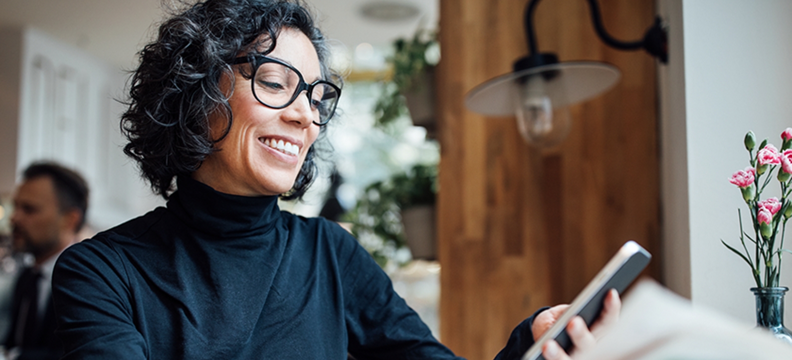 Woman sits in cafe with her smartphone in hand.