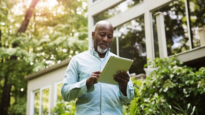 Person in front of house looking at tablet
